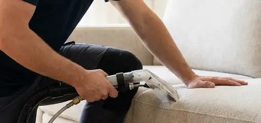 Professional upholstery cleaner deep-cleaning a fabric sofa with a handheld extraction tool, Bakersfield, CA.